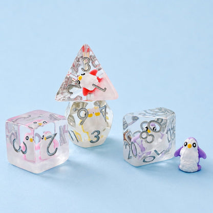 Colorful Penguin close-up of four clear resin embedded DND dice with penguin figures on a light blue background.