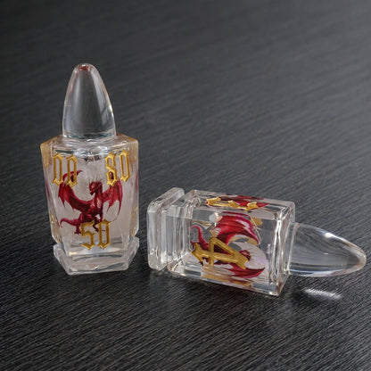 Dragonshot close-up of two clear bullet-shaped liquid core DND dice with red dragon motifs on a dark tabletop.