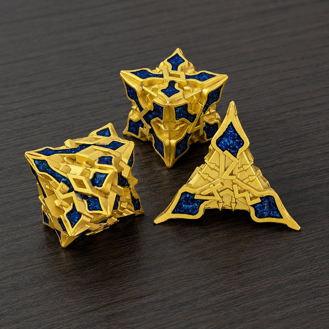 Golden Knight Series close-up of three gold-toned metal DND dice with blue glitter inlays on a dark wood tabletop.