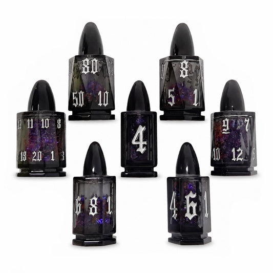 Midnight Assassin 7-piece black bullet-shaped liquid core DND dice set with iridescent flakes and silver numbers on white background.